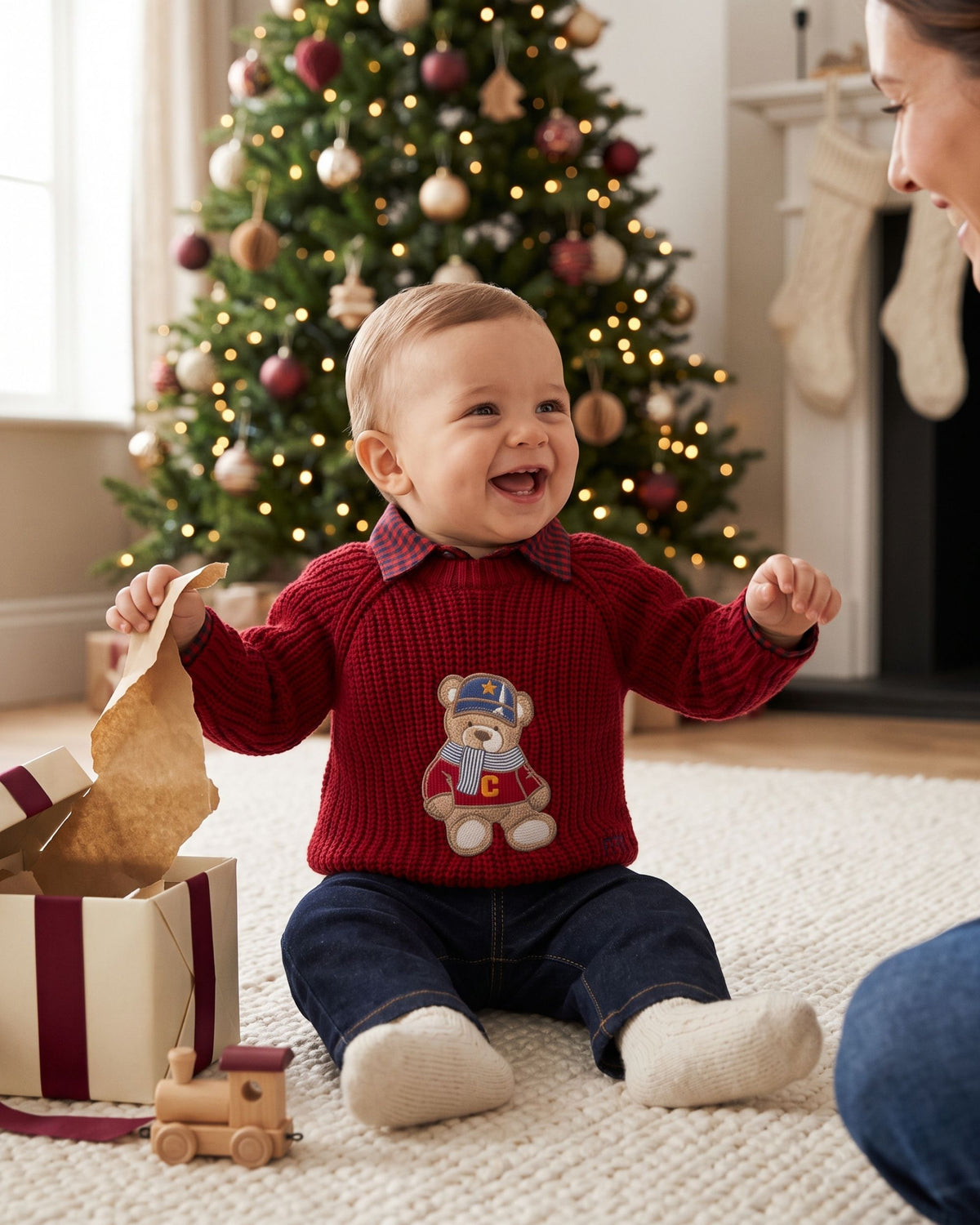 Baby boy wearing a red teddy Christmas jumper and jeans on Christmas morning