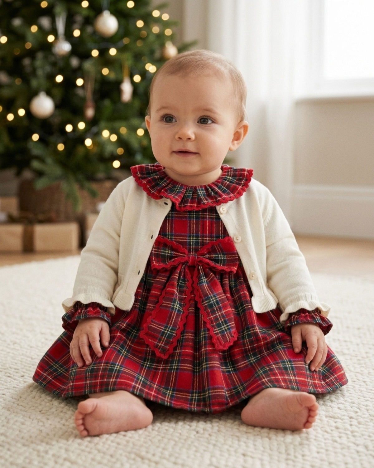 Baby girl wearing a cream knit cardigan over a dress at a christening
