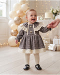 Baby girl wearing a houndstooth dress with lace collar at a family celebration