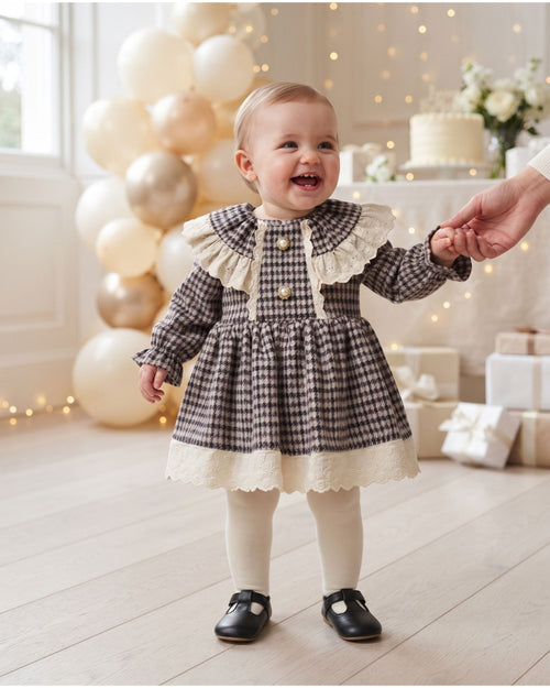Baby girl wearing a houndstooth dress with lace collar at a family celebration