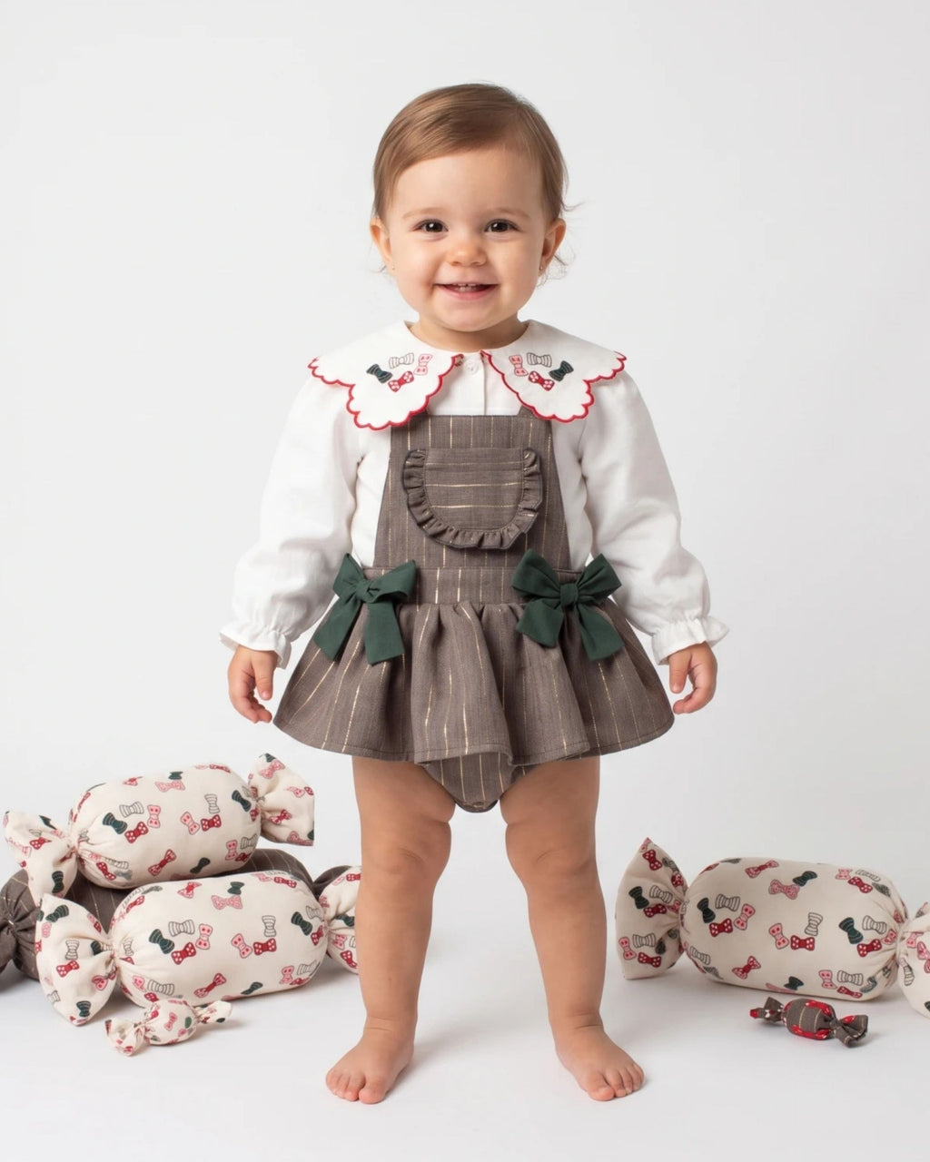Baby girl standing in a grey pinstripe pinafore romper and embroidered collar blouse
