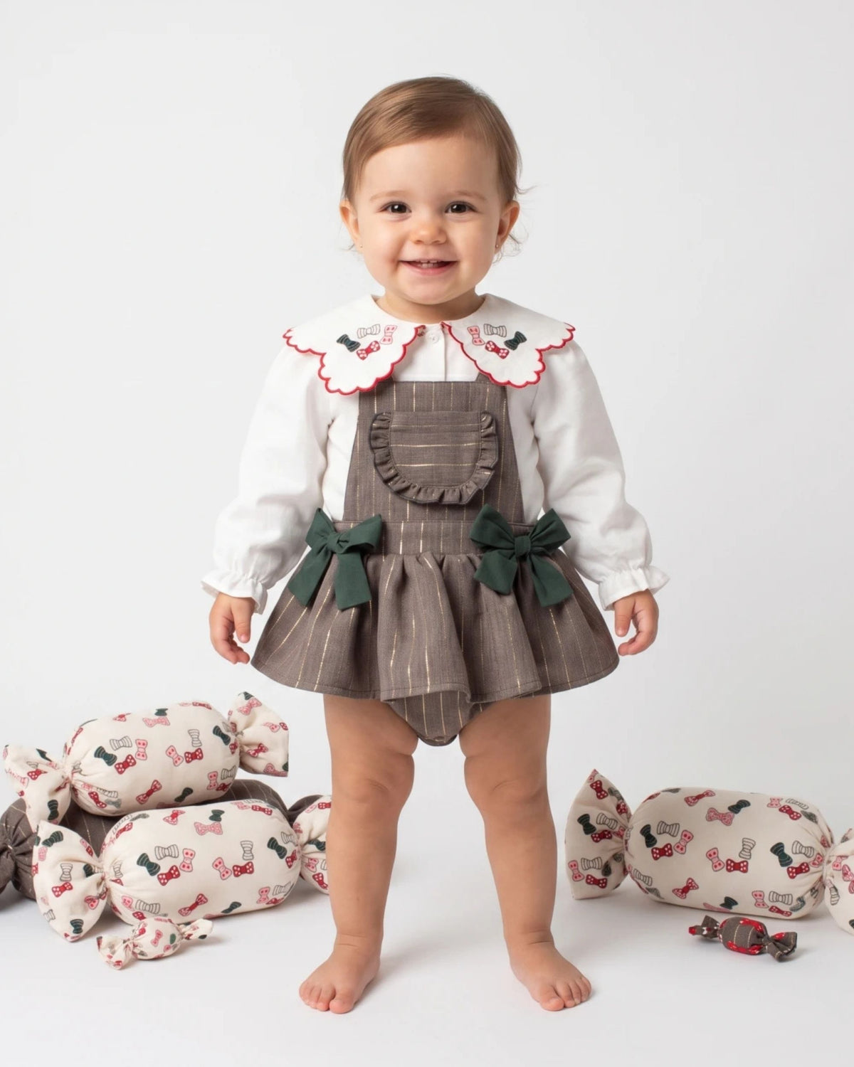 Baby girl standing in a grey pinstripe pinafore romper and embroidered collar blouse