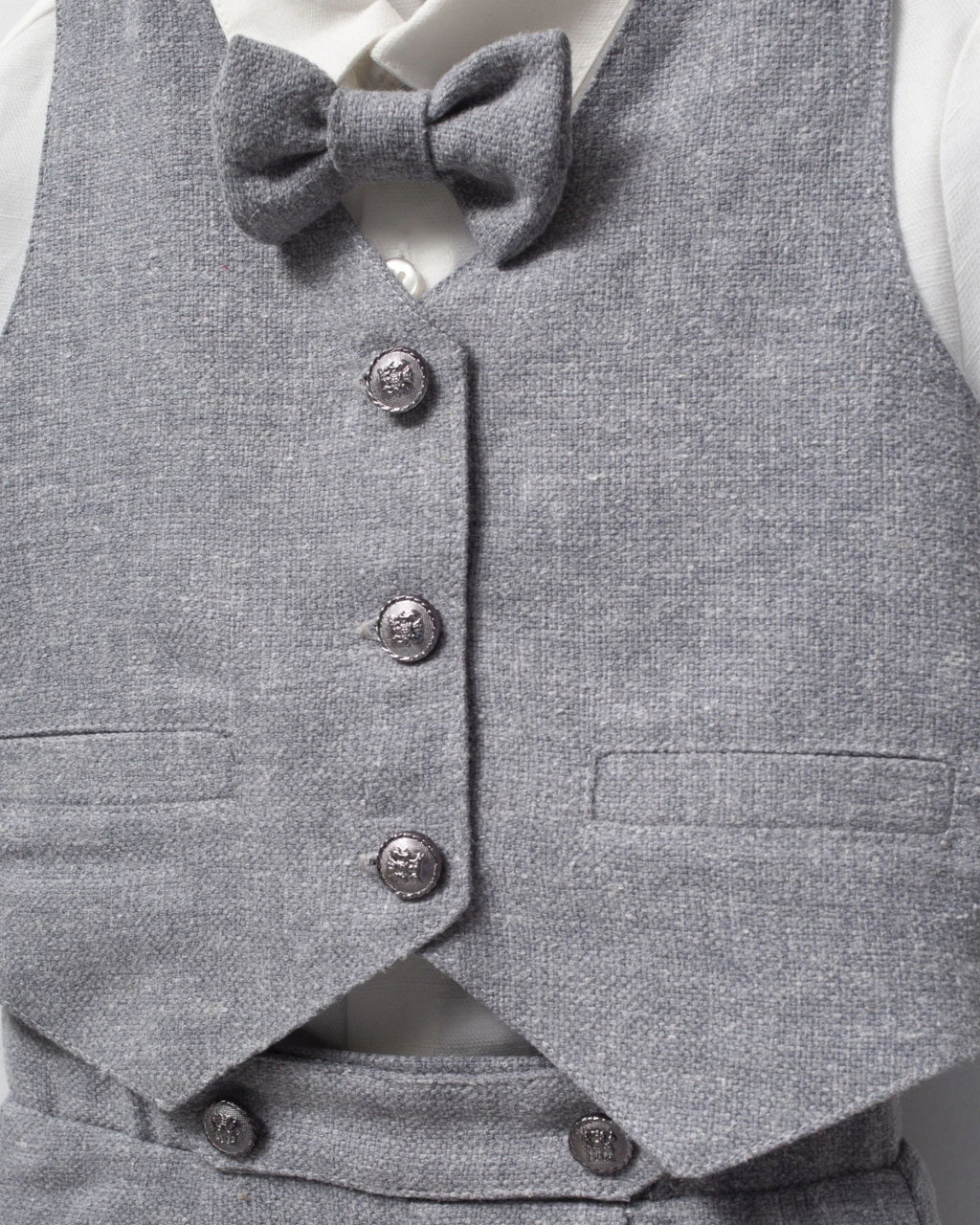 Close-up of grey waistcoat buttons, flap pockets and matching bow tie