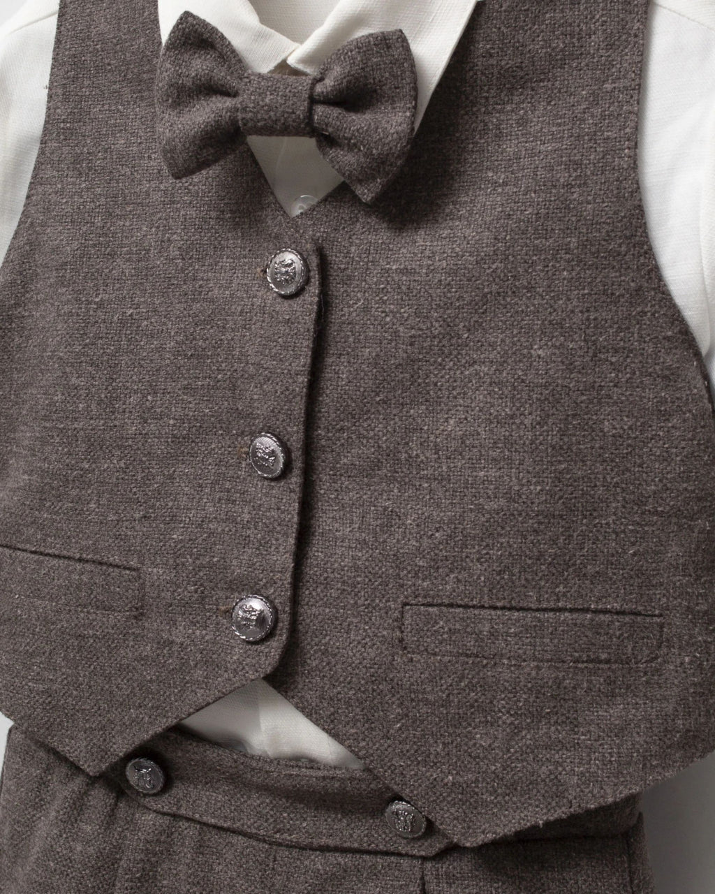 Close-up of brown waistcoat buttons, flap pockets and matching bow tie