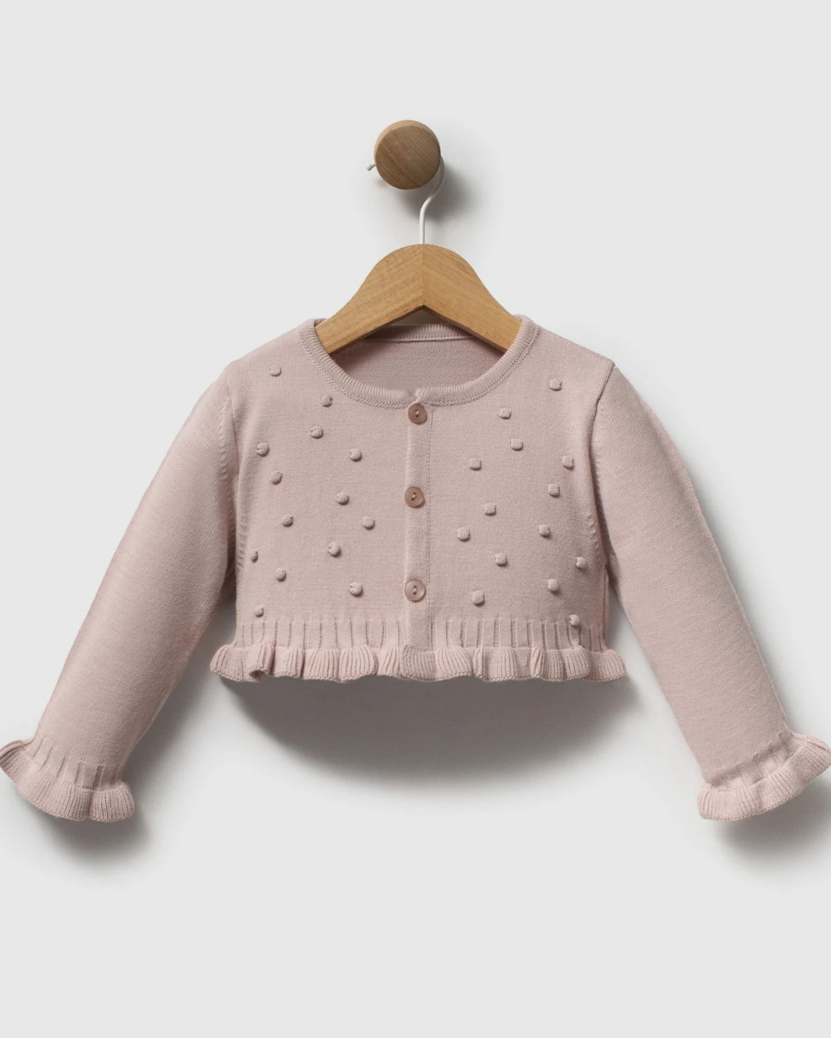 Pink gingham romper dress and knit cardigan laid flat with a christening card