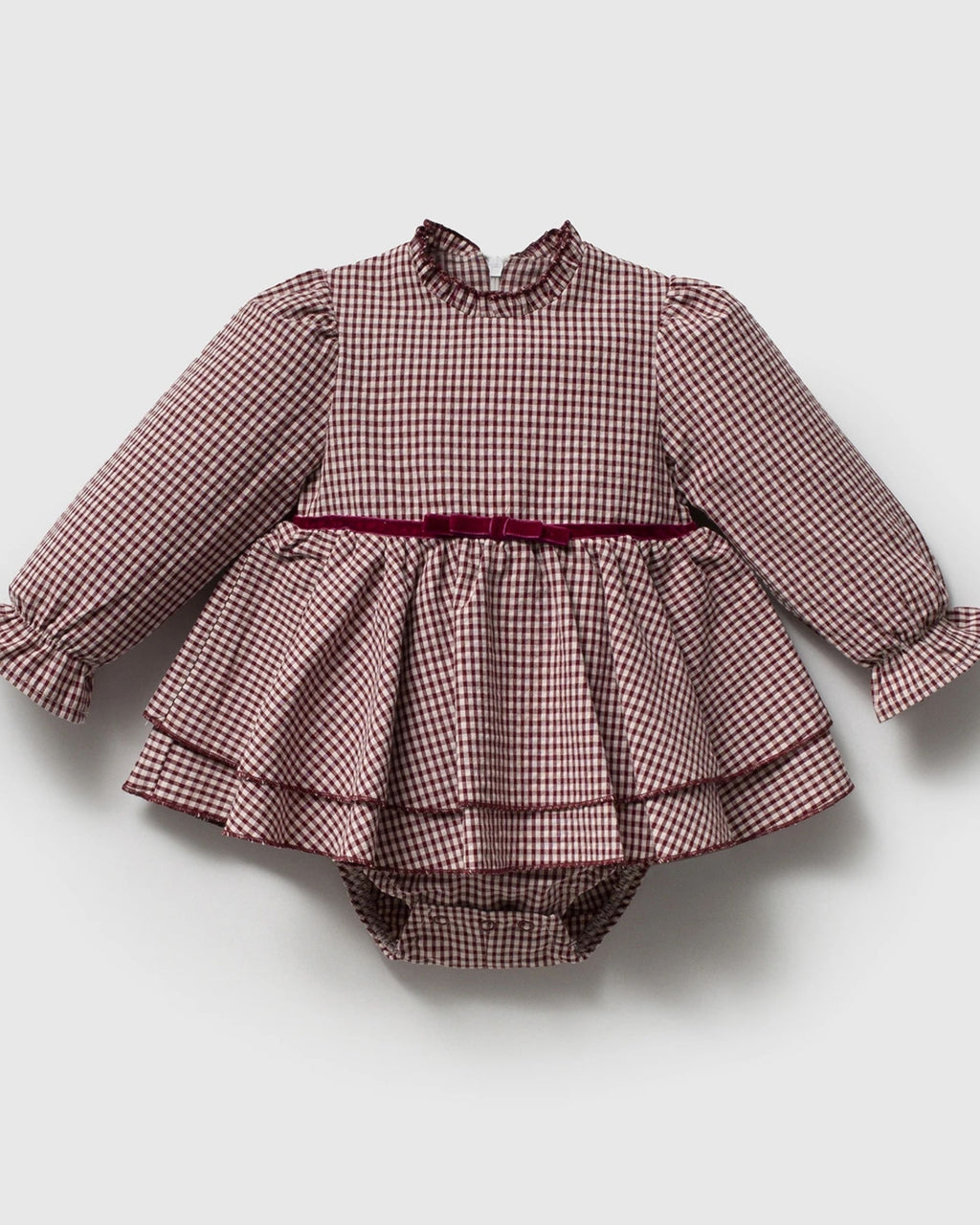 Close-up of frilled collar and velvet bow belt on a gingham baby romper