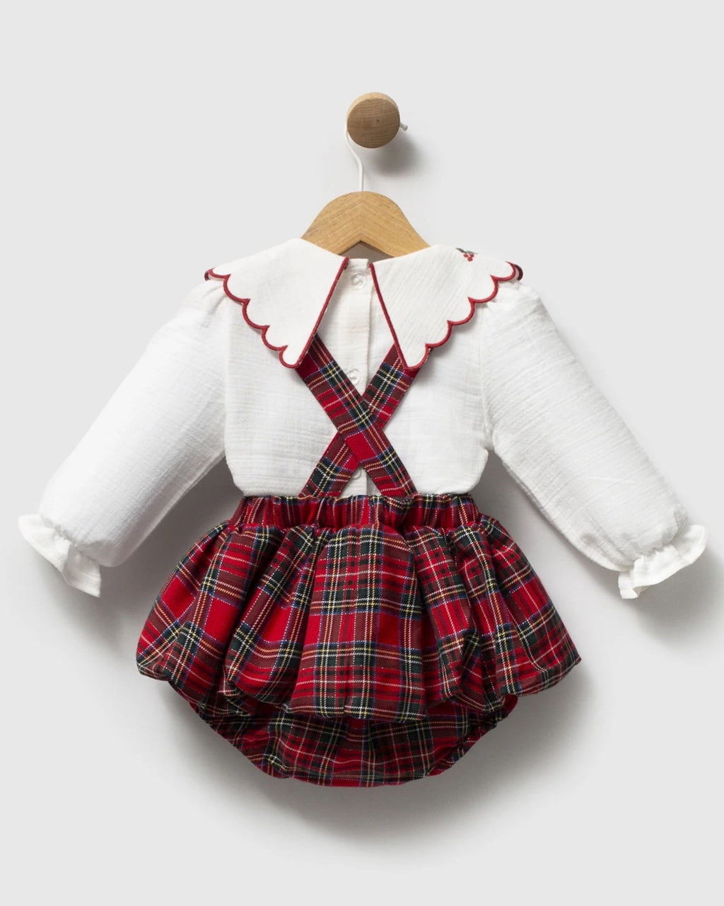 Back of red tartan baby romper with cross-back braces over ivory buttoned blouse