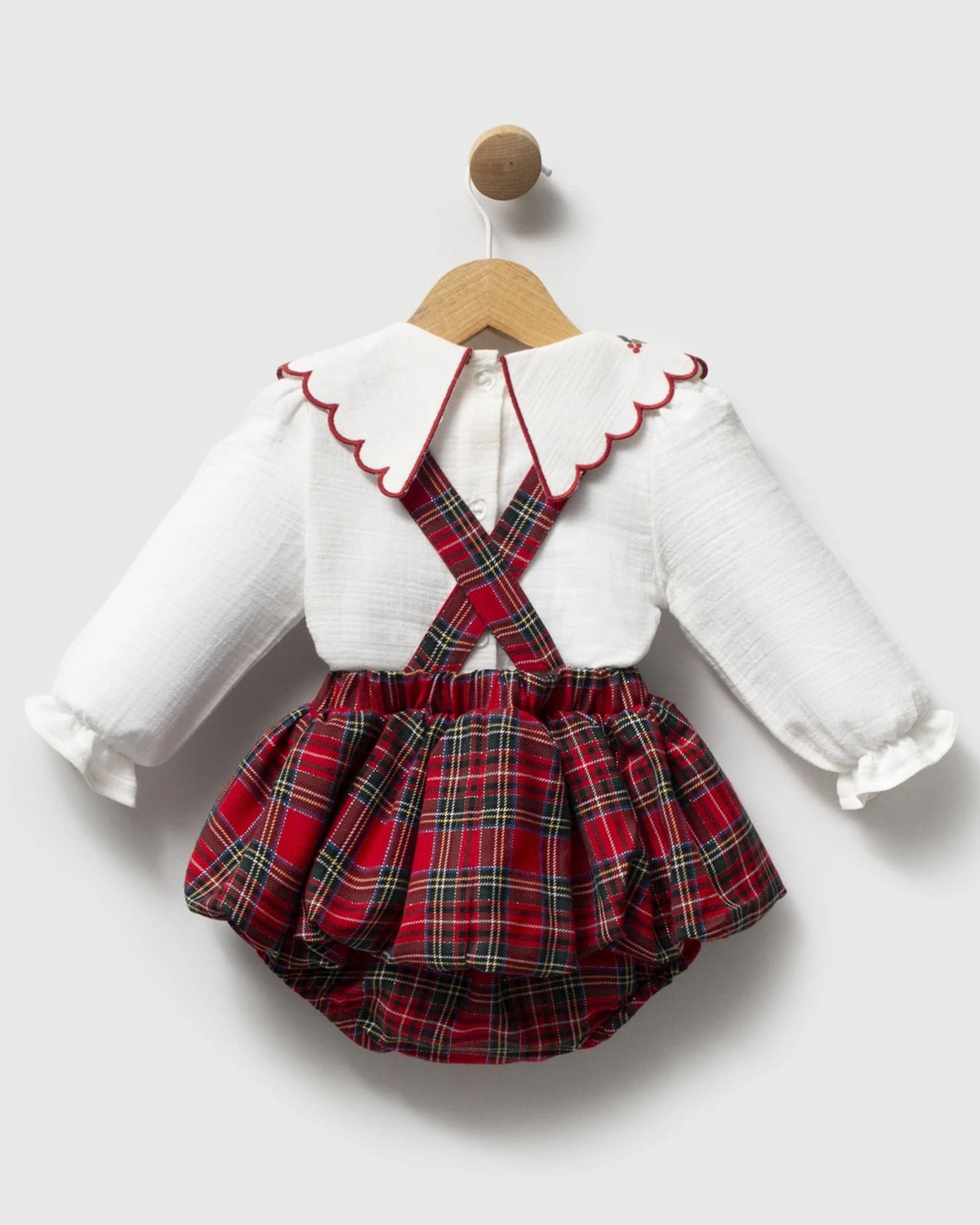 Back of red tartan baby romper with cross-back braces over ivory buttoned blouse