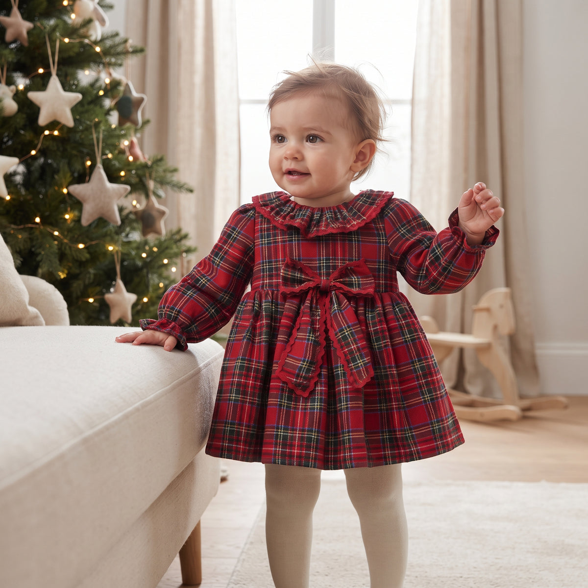 Baby girl wearing a red tartan dress with bow at a family Christmas