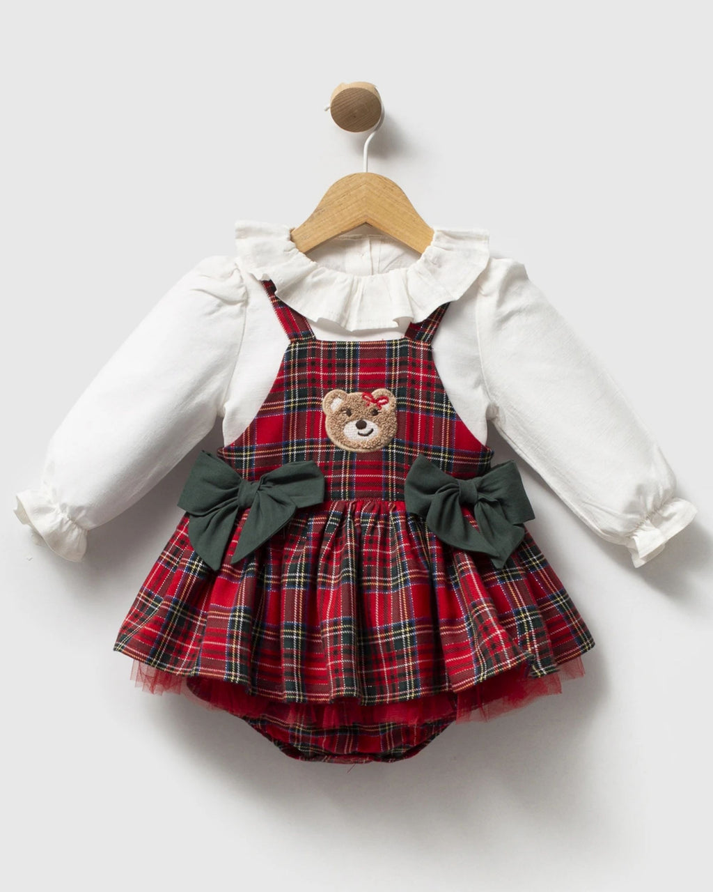 Close-up of embroidered teddy bear on a red tartan baby pinafore