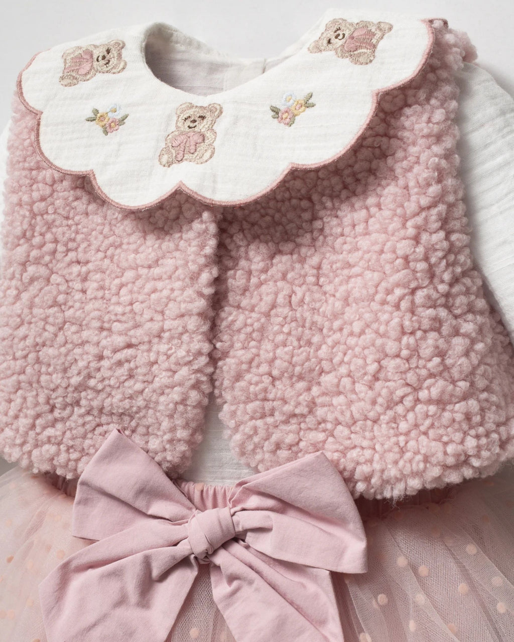 Close-up of tiny teddy bear embroidery on a baby blouse collar