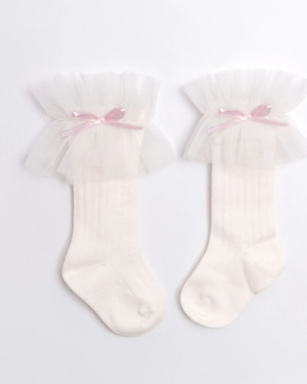 Close-up of tulle frill and pink satin bow on a white baby sock